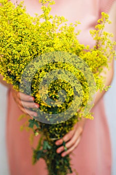 Young woman in a rosy dress holding a bunch of colorful picked w