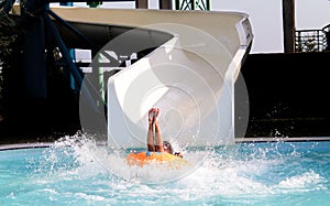 Young woman on rubber ring going down slide in aqua park