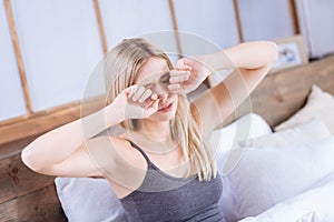 Young woman rubbing her eyes having woke up