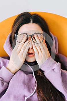 Young woman rubs her eyes after using glasses in front laptop. Eye pain or fatigue concept