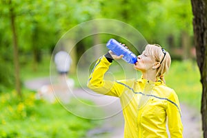 Young woman runner drinking water