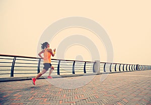 Young woman runner running at seaside