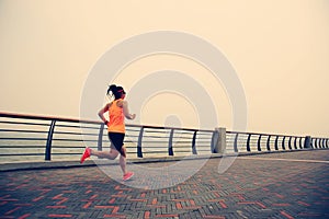 Young woman runner running at seaside