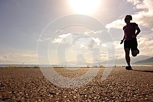 Young woman runner running on sunrise seaside