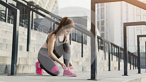 Young woman runner tying shoelace at stadium