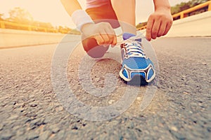 Young woman runner tying shoelaces