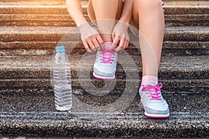 Young woman runner tying shoelaces. Exercise concept photo