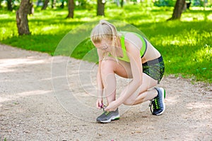 Young woman runner tying shoelaces and preparing for fitness