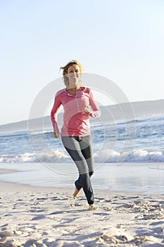 Young Woman Running Along Sandy Beach On Holiday