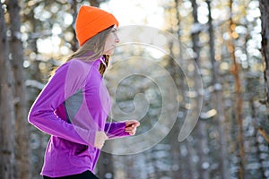 Young Woman Running in Beautiful Winter Forest at Sunny Frosty Day. Active Lifestyle Concept.