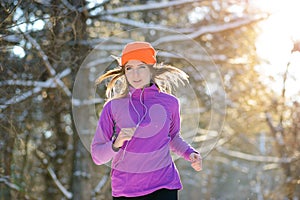 Young Woman Running in Beautiful Winter Forest at Sunny Frosty Day. Active Lifestyle Concept.