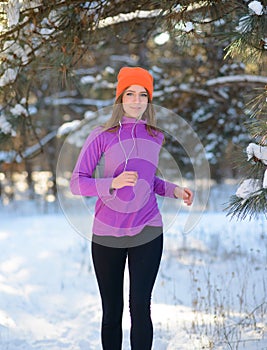 Young Woman Running in Beautiful Winter Forest at Sunny Frosty Day. Active Lifestyle Concept.