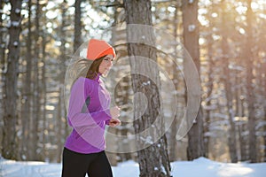 Young Woman Running in Beautiful Winter Forest at Sunny Frosty Day. Active Lifestyle Concept.