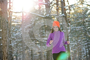 Young Woman Running in Beautiful Winter Forest at Sunny Frosty Day. Active Lifestyle Concept.