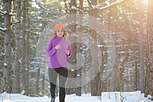 Young Woman Running in Beautiful Winter Forest at Sunny Frosty Day. Active Lifestyle Concept.