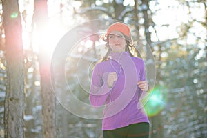 Young Woman Running in Beautiful Winter Forest at Sunny Frosty Day. Active Lifestyle Concept.