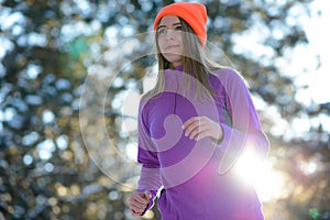 Young Woman Running in Beautiful Winter Forest at Sunny Frosty Day. Active Lifestyle Concept.