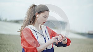 Young woman running and checking her cardio training data on her sport watch.