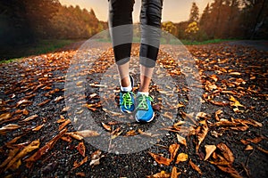 Young woman running in the early evening autumn leaves