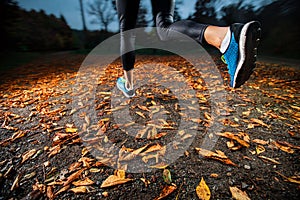 Young woman running in the early evening autumn leaves