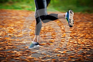 Young woman running in the early evening autumn leaves