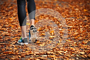 Young woman running in the early evening autumn leaves