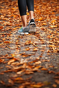 Young woman running in the early evening autumn leaves