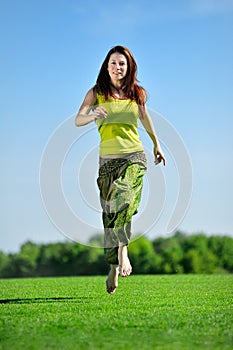 Young woman running on a green meadow