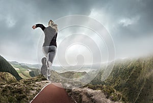 Young woman running and jumping near mountains and lake