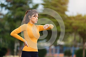 Young woman running and looking at her smart wrist watch in park