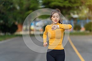 Young woman running and looking at her smart wrist watch in park