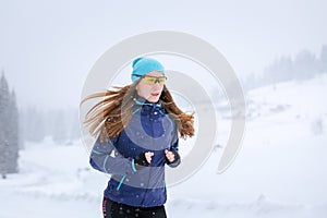 Young woman running on the mountain road in winter