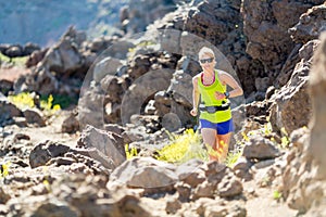 Young woman running in mountains on sunny summer day