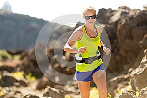 Young woman running in mountains on sunny summer day