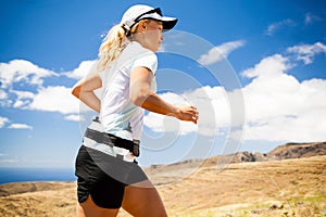 Young woman running in mountains on sunny summer d