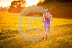 Young woman running outdoors on a lovely sunny summer evening