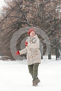 Young woman running in the park in winter. She is wearing warm clothes. Vertical frame