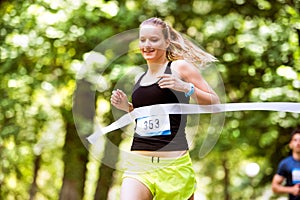 Young woman running the race crossing the finish line.