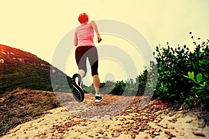 Young woman running on seaside mountain trail