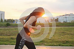 Young woman running at the stadium outdoor on the sunset