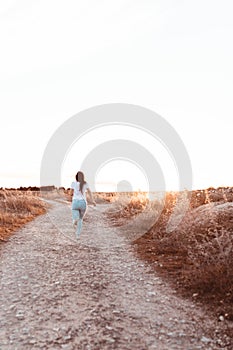 Young woman running at sunset in the field