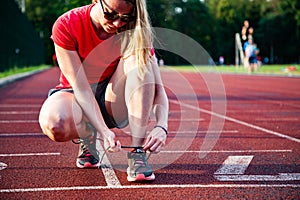 young woman on running track lacing her shoes