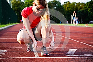 young woman on running track lacing her shoes