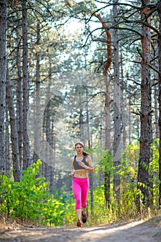 Young Woman Running on the Trail in the Beautiful Wild Pine Forest. Active Lifestyle Concept. Space for Text.