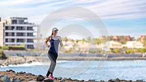 Young woman running on trail near the ocean coast