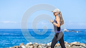 Young woman running on trail near the ocean coast