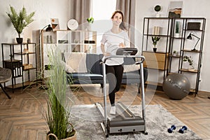 Young woman running on a treadmill at home. Female runner doing cardio exercise healthily lifestyle.