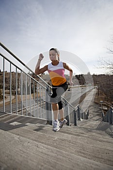 Young woman running up stairs in city.