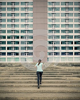 Young woman running up in urban stairs