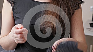 Young woman runs comb along dark brown hair and shows brush